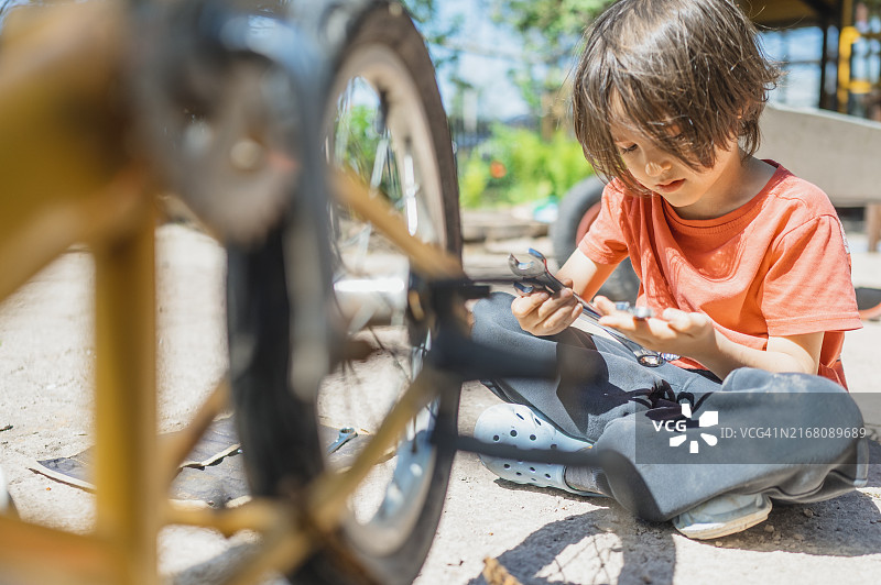 男孩在后院手持扳手盘腿而坐图片素材