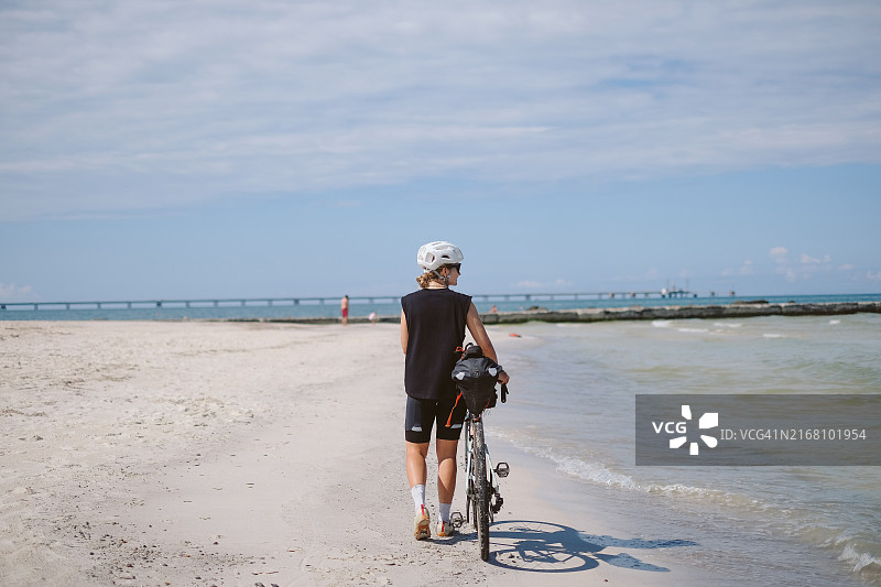 年轻女子在海滩上骑自行车图片素材