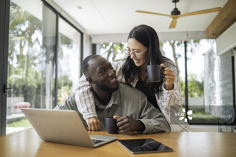 与黑人男子一起喝咖啡进行远程工作的亚洲女人图片素材