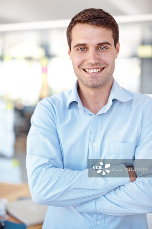 商务男士在办公室交叉双臂，面带微笑，自信满满图片素材