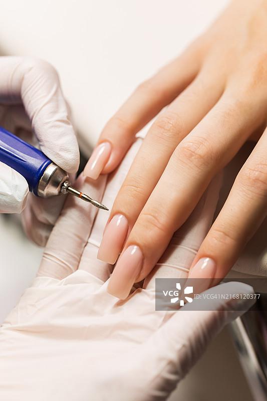 美甲师用设备为女性双手打磨指甲图片素材