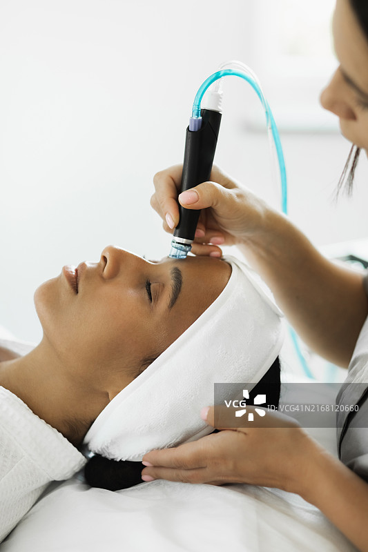 美丽的非洲女孩在水疗中心接受美容护理的面部特写图片素材