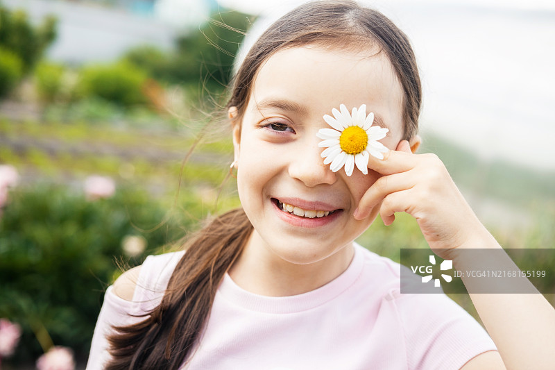 快乐小女孩的夏日写真：用雏菊花遮住眼睛图片素材