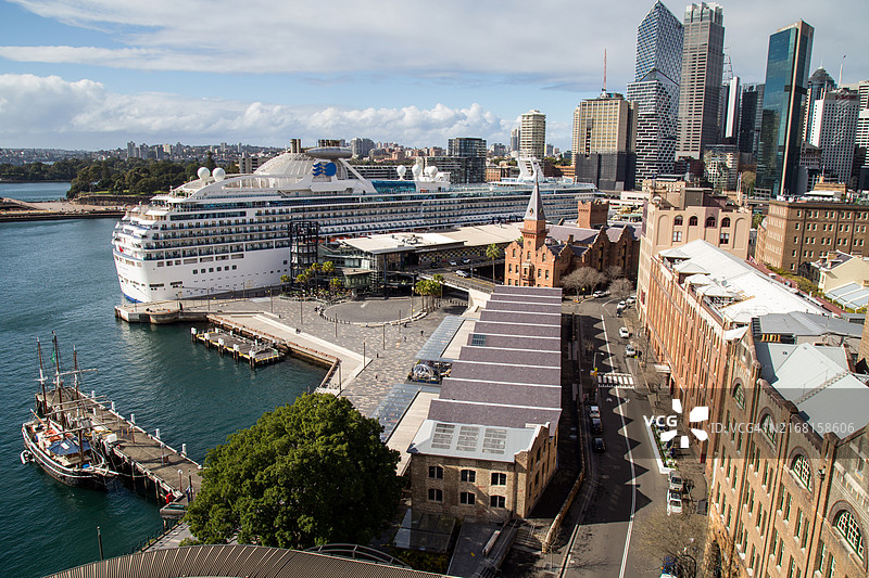 澳大利亚悉尼岩石区历史仓库的工业砖，背景是停靠的游轮和城市天际线图片素材