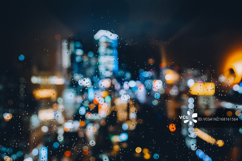雨天玻璃窗外灯火通明的城市夜景虚焦景观，城市散景图片素材