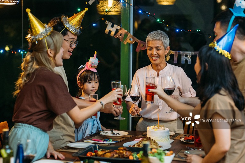 在室内庆祝生日的快乐亚洲家庭的暖色调肖像图片素材