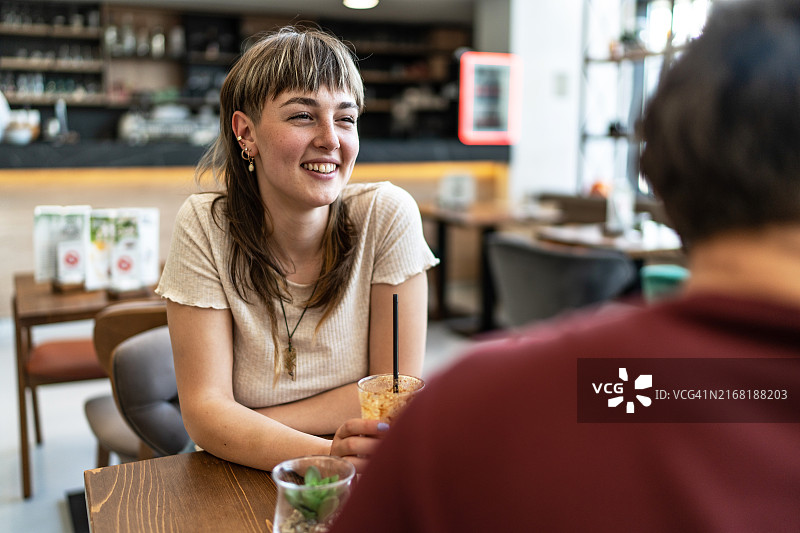 年轻女人在咖啡店里微笑，男人感受到爱和幸福图片素材