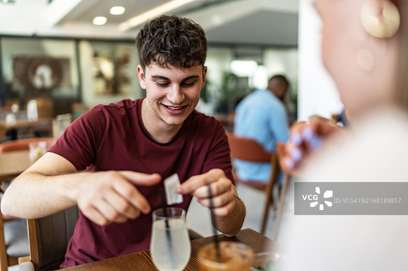 年轻男人在柠檬水中加入糖图片素材