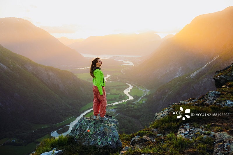 女徒步者欣赏山中壮丽的日落美景和山谷风光图片素材
