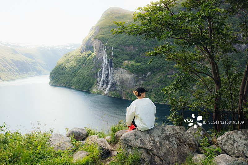 妇女沉思于田园诗般的北欧风光，瀑布和盖朗厄尔峡湾图片素材