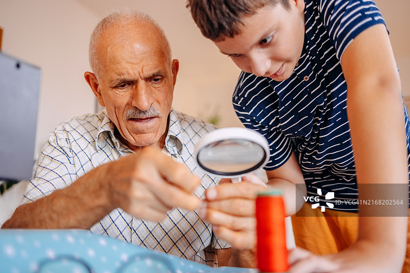 青少年孙子帮祖父母穿针引线图片素材