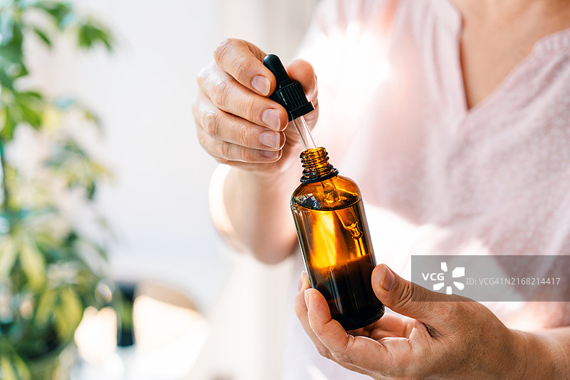 女人手拿滴管和琥珀色精油瓶，身体护理概念图片素材