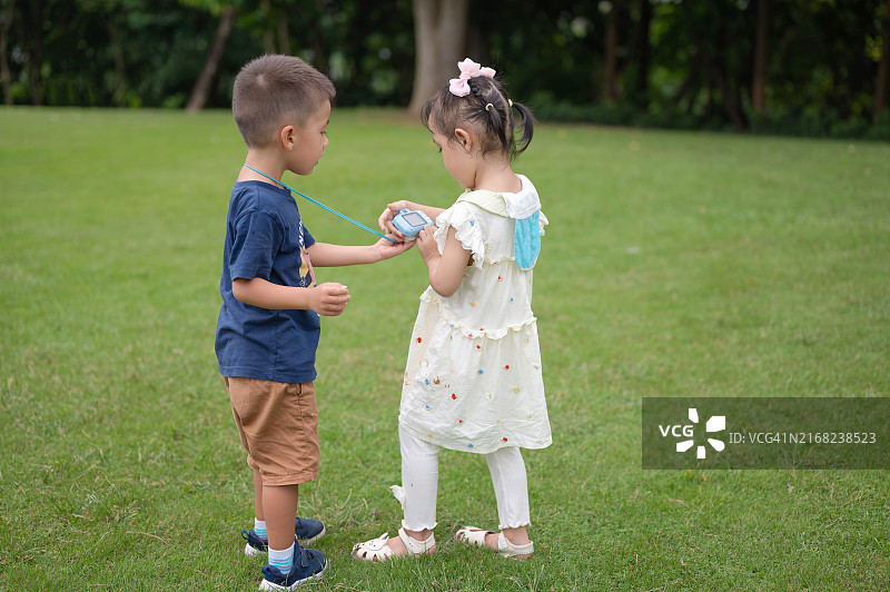 在公园里和女孩分享照片的男孩图片素材