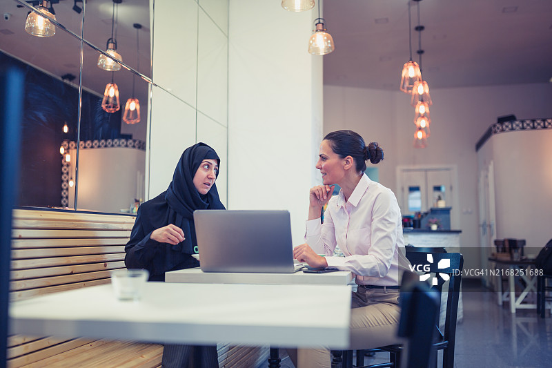两个女人在现代咖啡馆合作图片素材