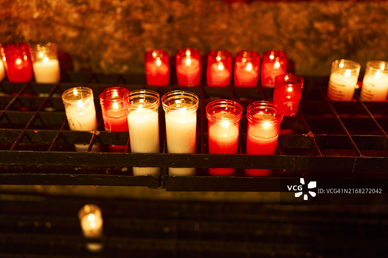 教堂内红色玻璃杯中的一组点燃的蜡烛（高角度）图片素材