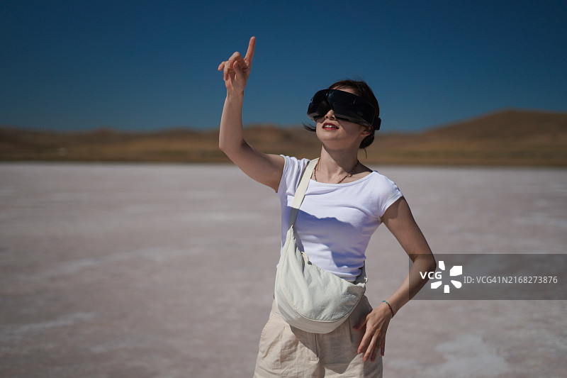 年轻亚洲女性游客在土耳其孔亚盐湖使用VR眼镜图片素材