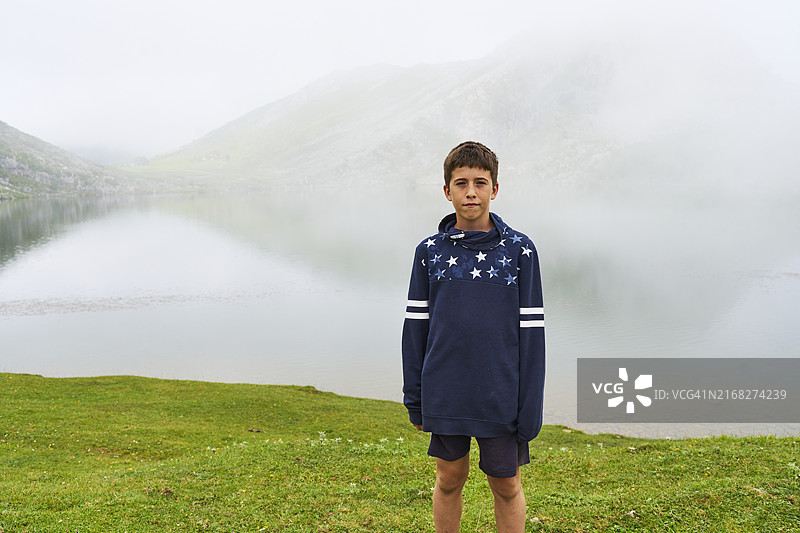 湖岸边，穿着蓝色毛衣的男孩正面照图片素材