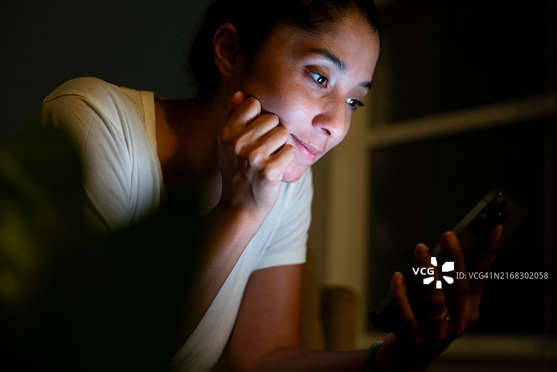 夜晚在家用手机的非裔美国妇女图片素材