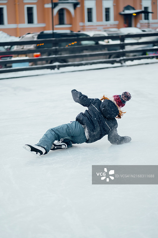 小男孩溜冰时不慎摔倒，躺在冰面上，身穿冬装，表情坚定图片素材