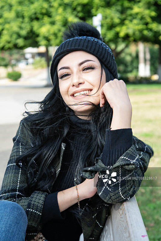 年轻漂亮女子独自坐在秋日长椅上的肖像图片素材