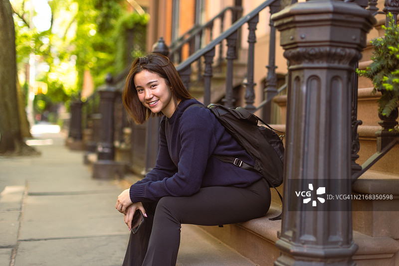 放松的年轻女子坐在春天早晨的城市台阶上图片素材