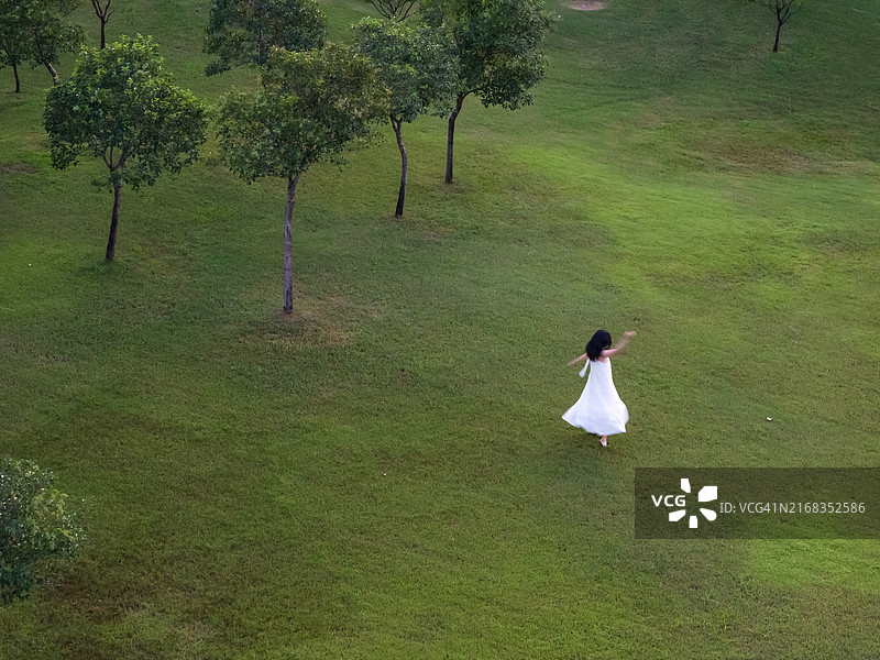 一位穿着长白裙的女性在公园里。图片素材
