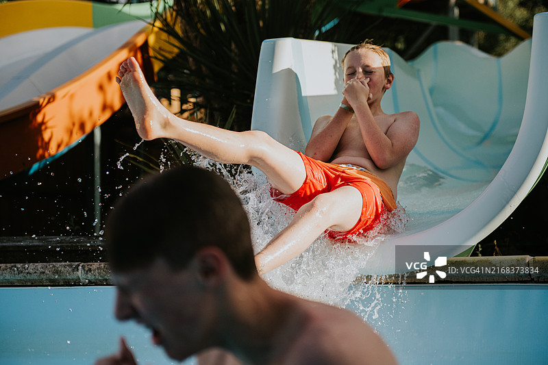 在水上乐园滑梯末端飞出时捏着鼻子准备迎接冲击的男孩图片素材