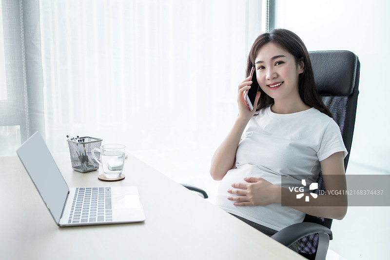 在咖啡馆午休时使用电脑和手机的孕妇图片素材