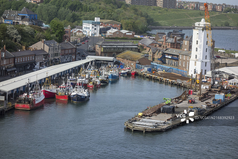 港口区域，有许多渔船和仓库、工业起重机和岸边的造船厂活动，英国纽卡斯尔图片素材
