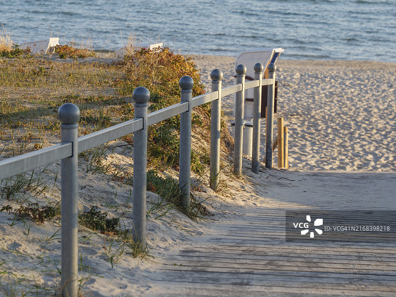 带栏杆的木板小路通向海滩和蓝天下的大海，周围环绕着沙丘，宾茨，德国图片素材