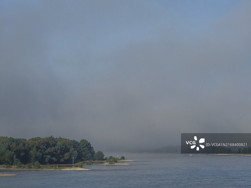 韦塞尔，德国北莱茵-威斯特法伦州，宁静的河流，河岸和树木笼罩在薄雾中，气氛祥和图片素材