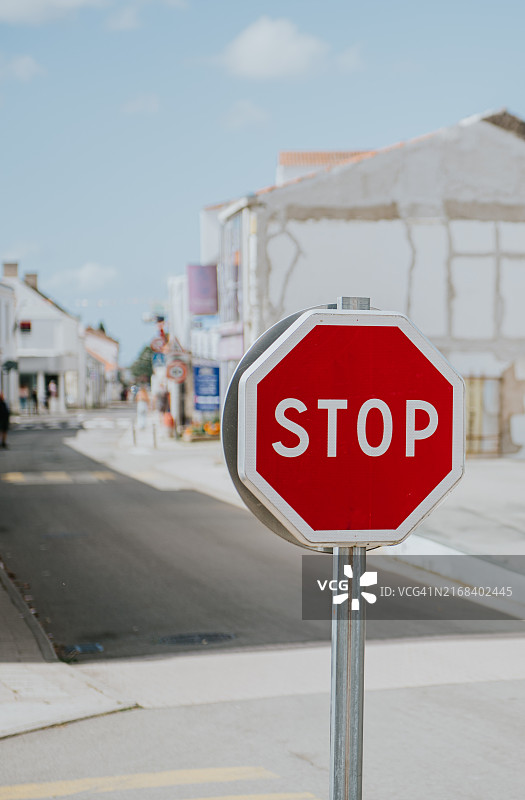 蓝天下白色建筑街道上的红色停止标志图片素材