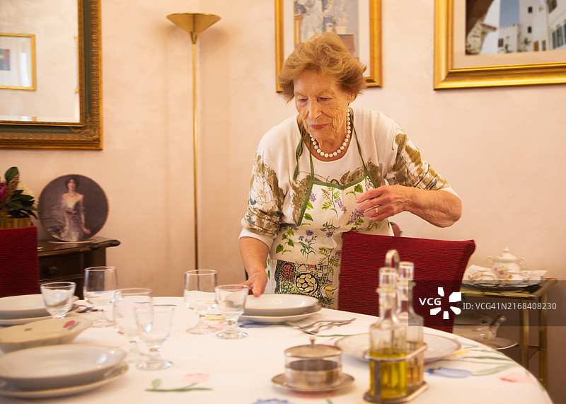年长的女人在餐厅里摆餐桌图片素材