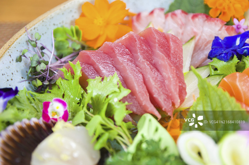 装饰精美的刺身寿司拼盘（三文鱼、金枪鱼、大比目鱼、焦香三文鱼），选择性聚焦图片素材