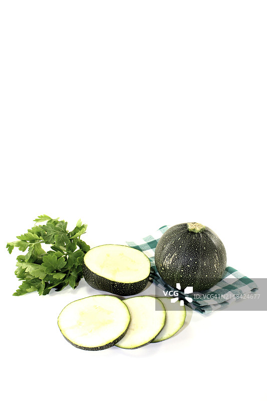 浅色背景下的绿色餐巾上的圆形生西葫芦图片素材