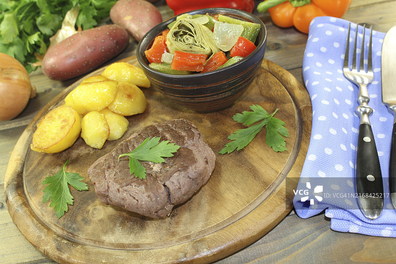 木板上烤鸵鸟肉排、带皮土豆和欧芹图片素材
