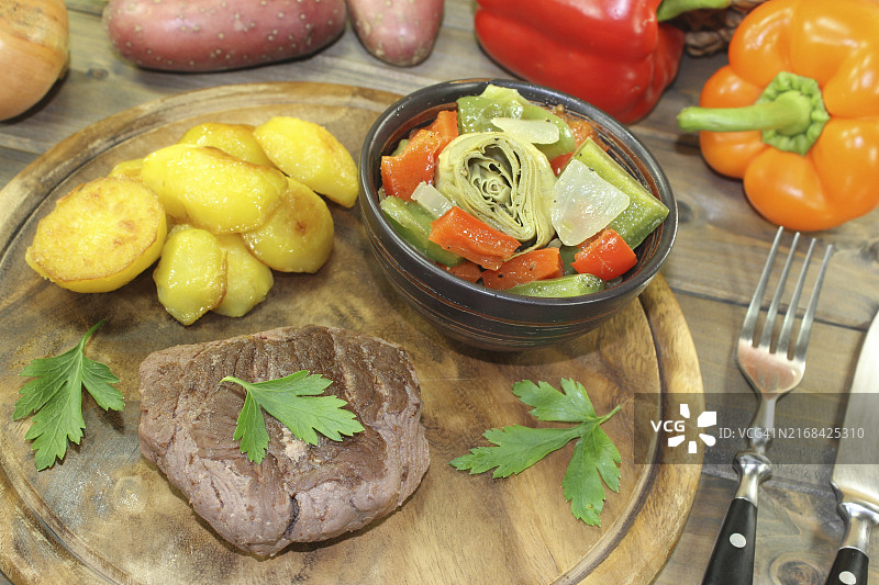 木板上的鸵鸟排、烤土豆和蔬菜图片素材