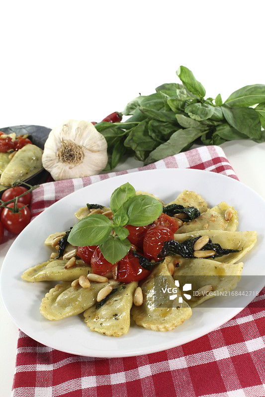 新鲜芝麻菜和乳清干酪饺子配松子、番茄和罗勒图片素材