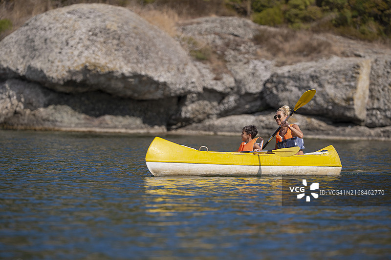 男孩和他的母亲在夏季度假时在河上划皮划艇图片素材