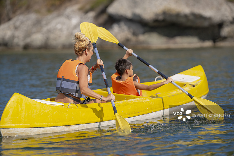 男孩和他的母亲在夏季度假时在河上划皮划艇图片素材
