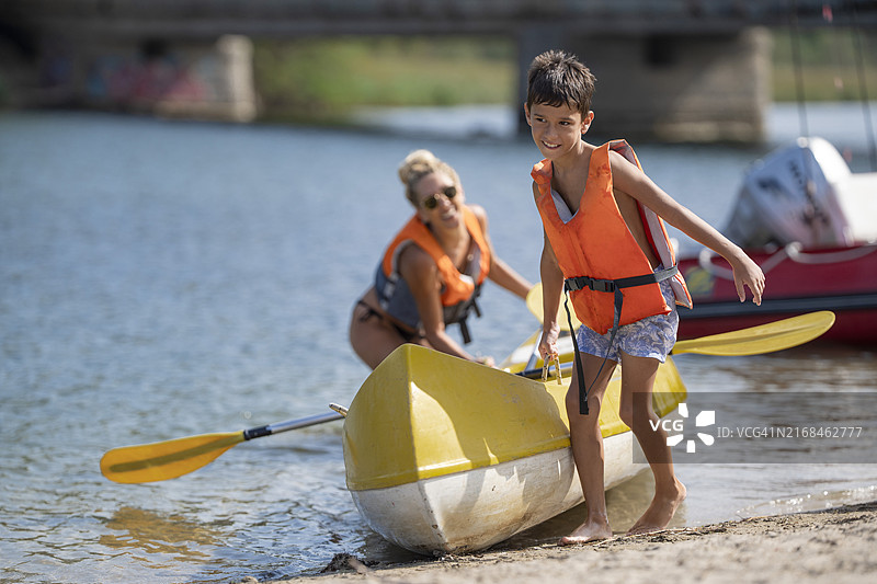 男孩和他的母亲在夏季度假时在河上划皮划艇图片素材