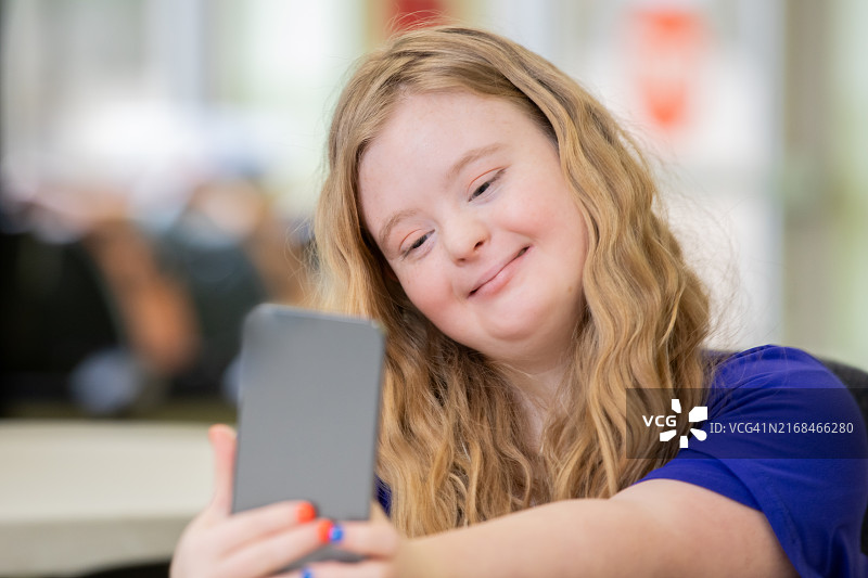 患有唐氏综合征的少女用手机自拍，做着鬼脸图片素材