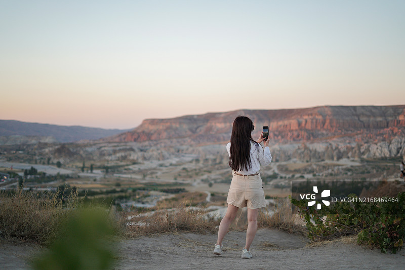 在卡帕多奇亚内夫谢希尔土耳其用智能手机拍照的年轻女游客图片素材