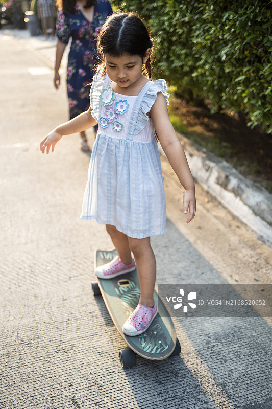 在车道上学习滑板的小女孩图片素材