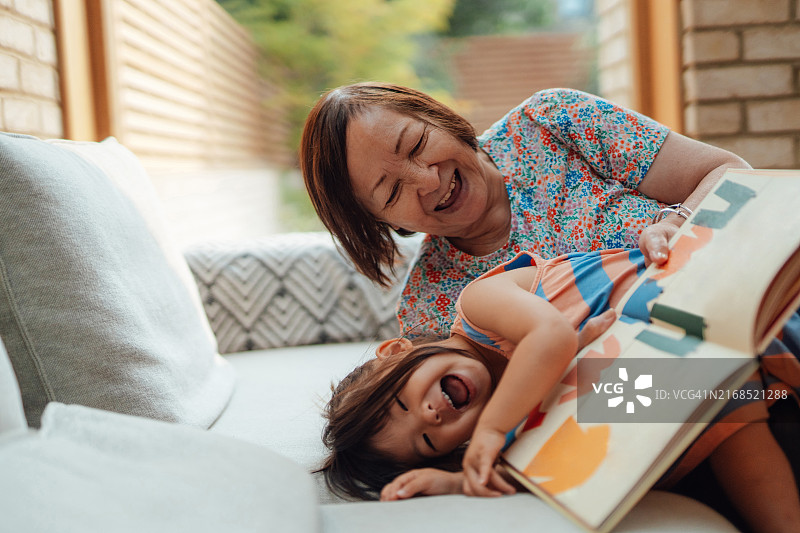 亚洲祖母在给孙女读书时感到快乐图片素材