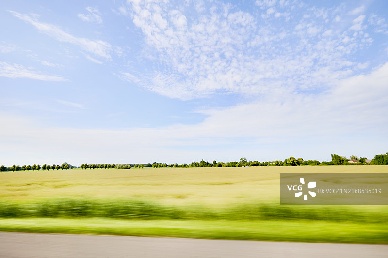 在高速行驶的汽车上，模糊的田野和夏季风景图片素材
