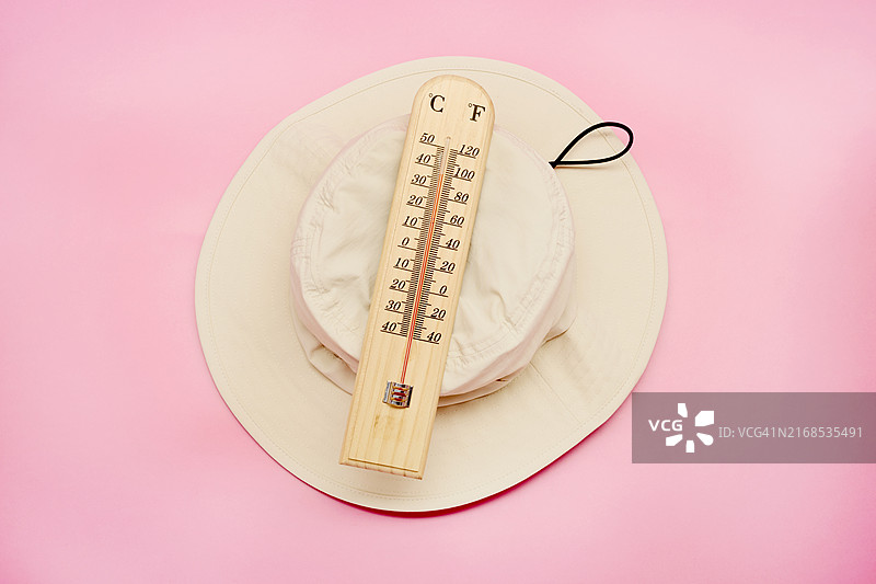 粉色背景上太阳帽上的温度计图片素材