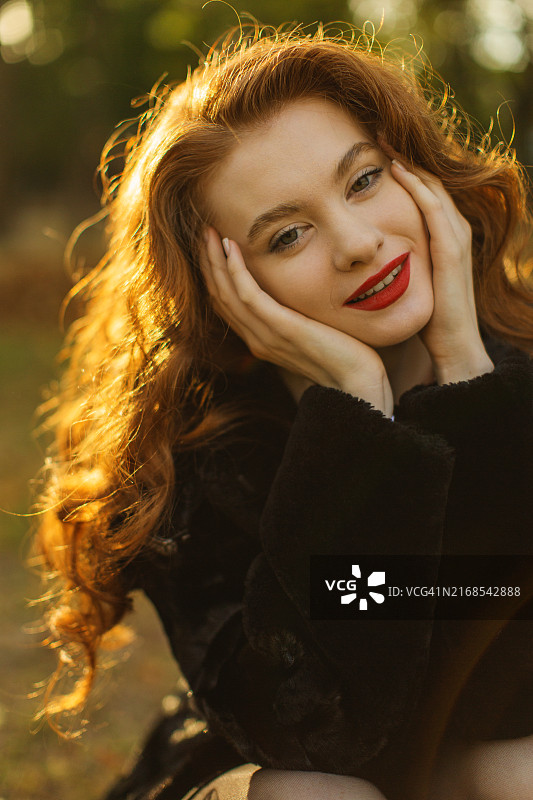 在秋日公园里身穿皮草外套的红发女人图片素材