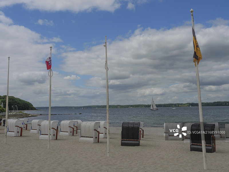 德国石勒苏益格-荷尔斯泰因州格吕克斯堡沙滩上的沙滩椅和旗帜，海上有帆船图片素材