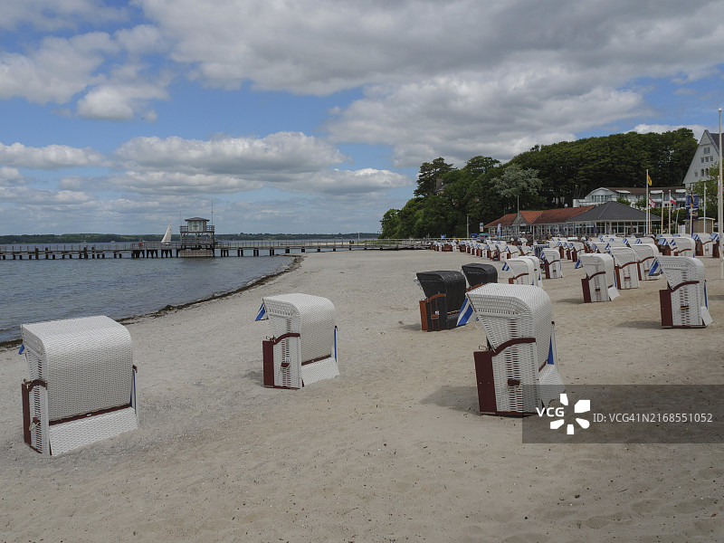 德国石勒苏益格-荷尔斯泰因州格尔克斯堡，海岸建筑和码头附近的沙滩上摆满了沙滩椅图片素材